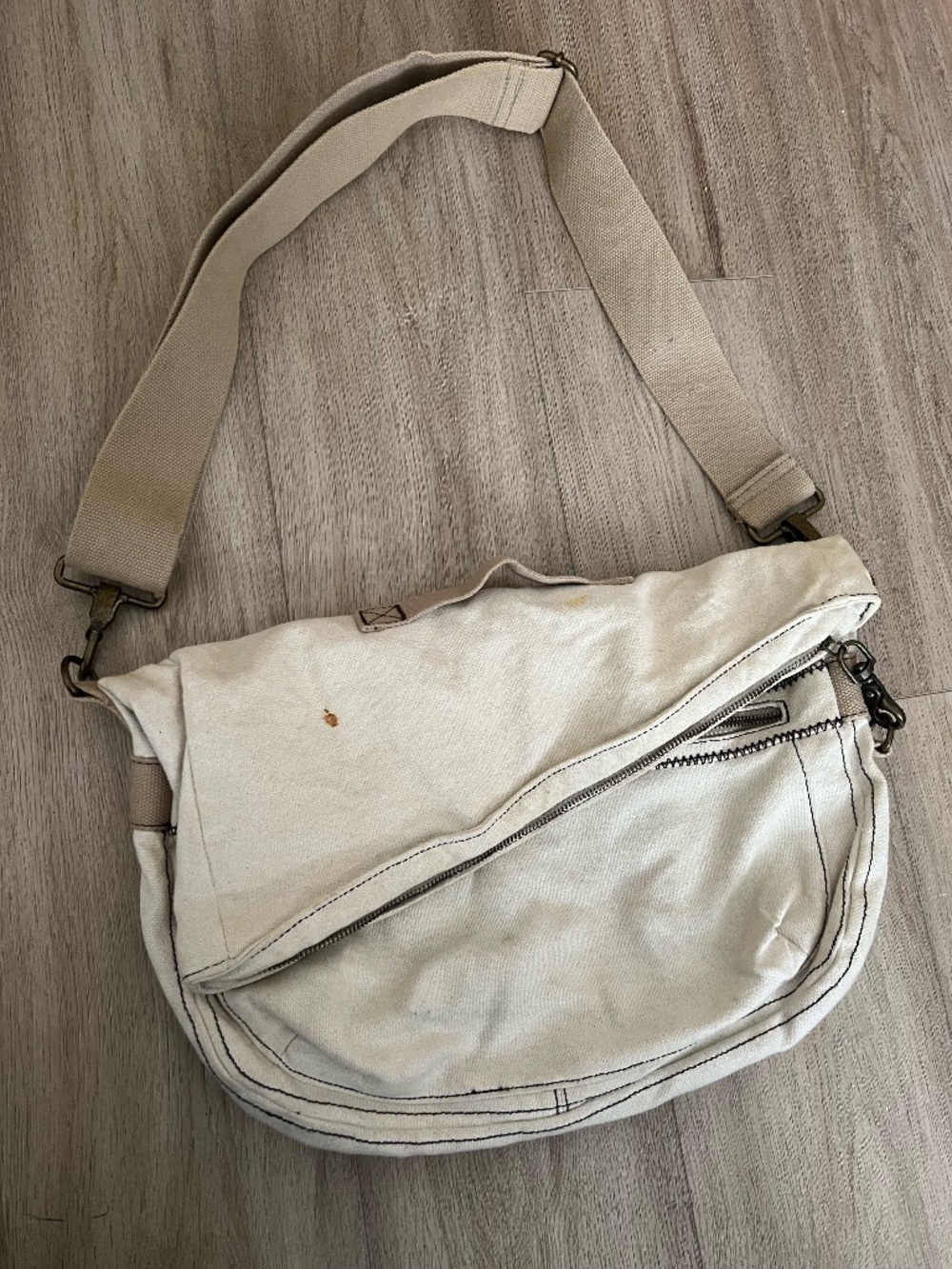 cream canvas messenger bag with adjustable strap, minor stains